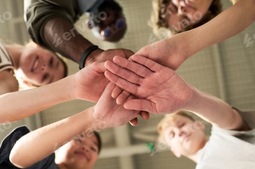 Preview: Diverse Group of Teenagers and Adult Man Stacking Hands in Teamwork Gesture
