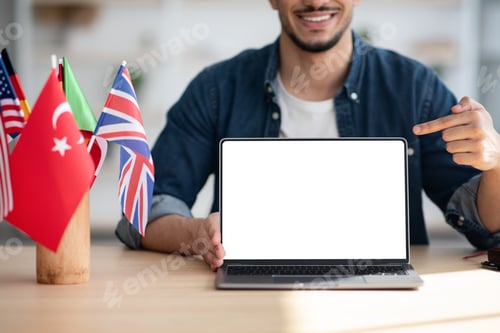 Preview: Cropped of arab man pointing at laptop with blank screen