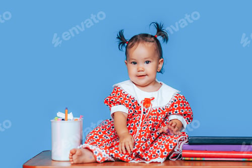 Preview: Cute one year old mixed race Asian Caucasian german girl wearing red dress smiles sweetly looking at