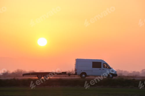 Preview: Tow truck vehicle with car carrier trailer driving on highway in evening