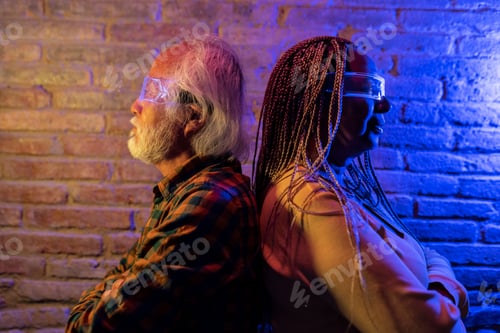 Preview: Multiracial senior couple with their backs to each other wearing futuristic glasses