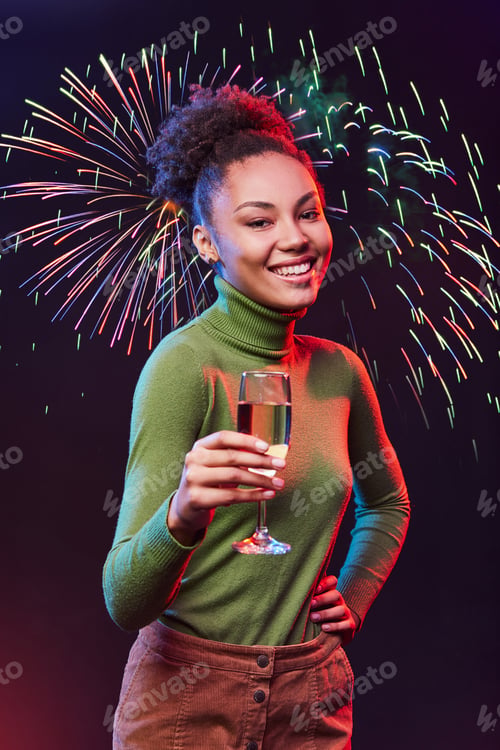 Preview: Portrait of a young beautiful mixed race woman holding glass of champagne and smiling at camera