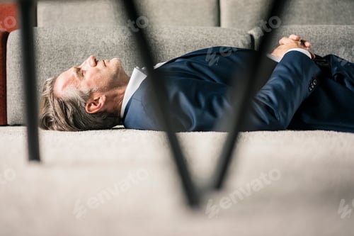 Preview: Mature businessman lying on carpet with closed eyes