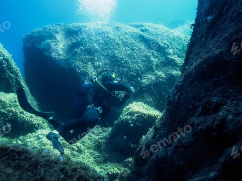 Preview: man diving by the sea water near the rocky bottom
