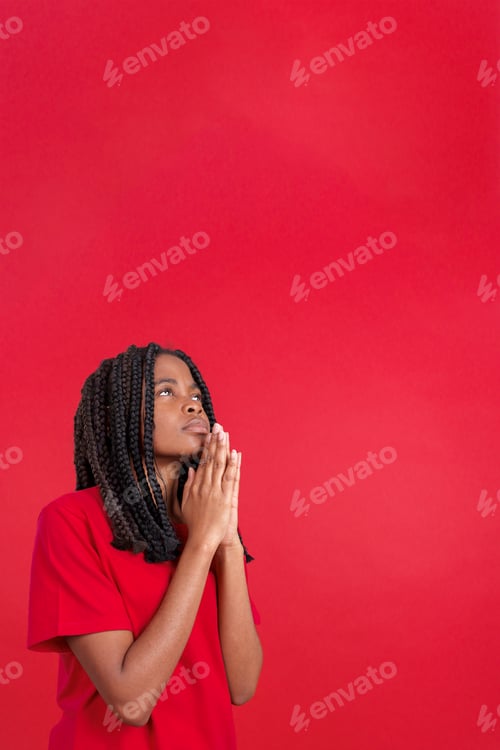 Preview: African woman looking up while praying with folded hands
