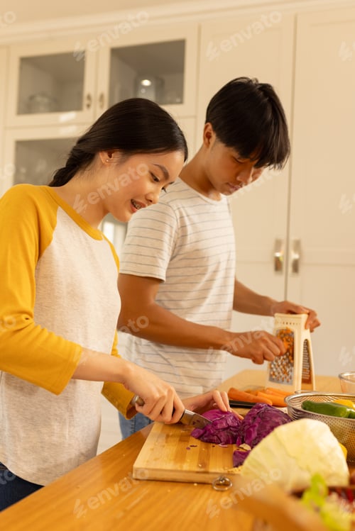 Preview: chopping vegetables asian brother and sister preparing meal together in kitchen