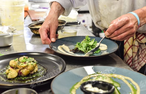 Preview: Experienced chef working in a professional kitchen, skillfully preparing a meal