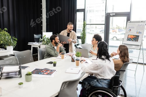 Preview: interracial startup team discussing project and sharing ideas, businesswoman in wheelchair