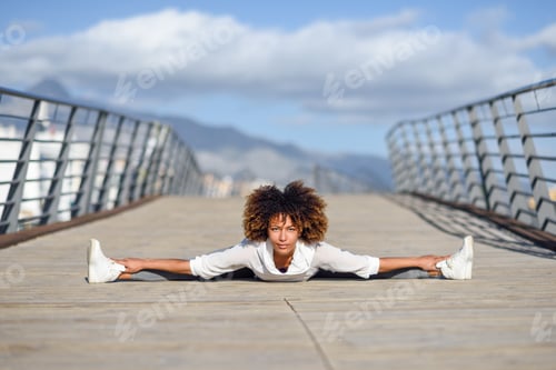 Preview: Young black woman doing stretching after running outdoors