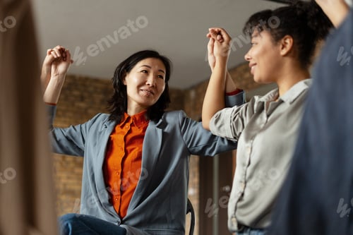 Preview: Businesswomen holding hands during meeting celebrating success