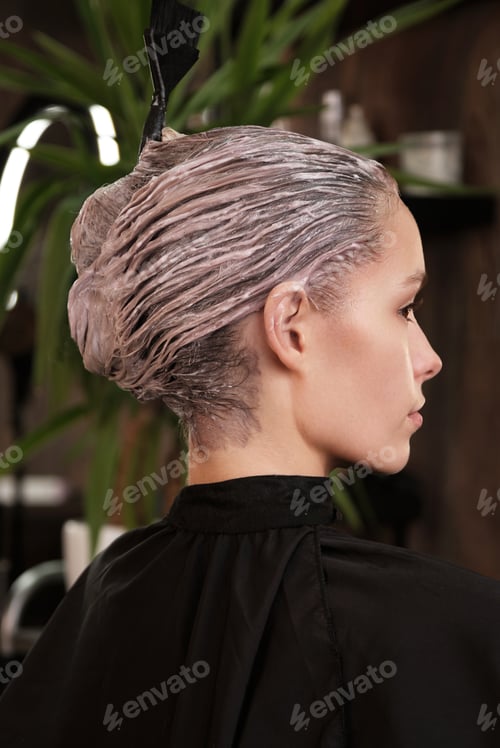 Preview: Young woman in a hairdressing salon dyes her hair blond and washing head
