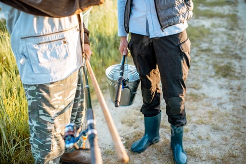 Preview: Holding fishing rods and bucket with fish outdoors