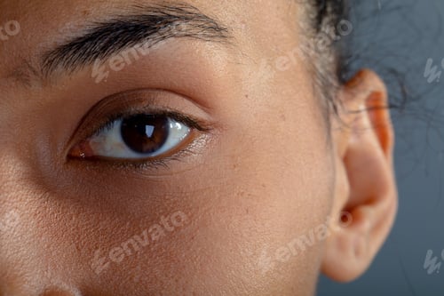 Preview: Close up of eye of african american businesswoman against grey background
