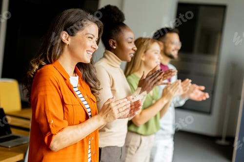 Preview: Young multiethnic startup team standing and applauding in the modern office