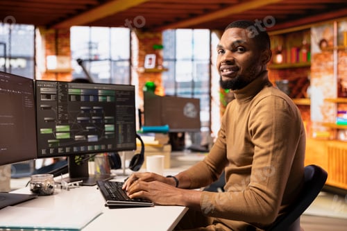 Preview: Portrait of smiling IT expert using PC in startup office to implement algorithms