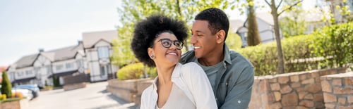 Preview: positive african american couple looking at each other on urban street in summer, banner