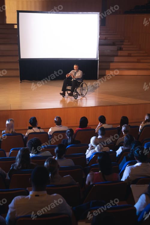 Preview: usinessman sitting on a wheelchair and giving presentation to the audience in the auditorium