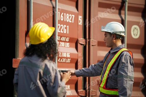 Preview: Workers discussing cargo details at a shipping container site in the afternoon sun
