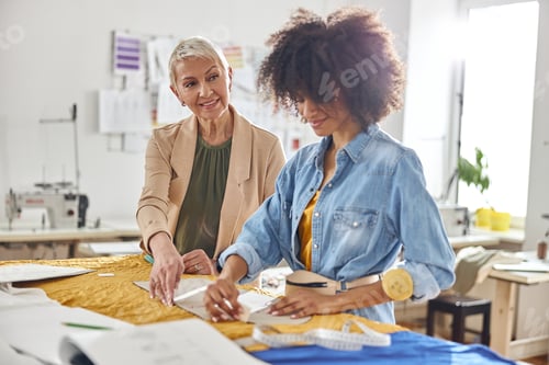 Preview: Dressmaker helps African-American seamstress to work with sewing pattern in modern studio