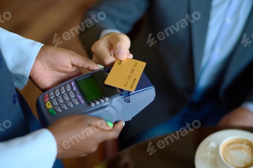 Preview: Hand of young businessman holding credit card over payment terminal