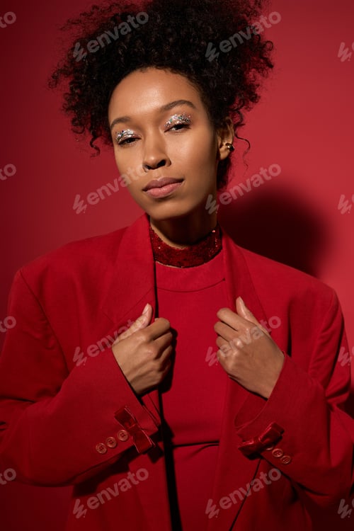Preview: Beautiful young woman with sparkling makeup against a rich red background showcasing elegance