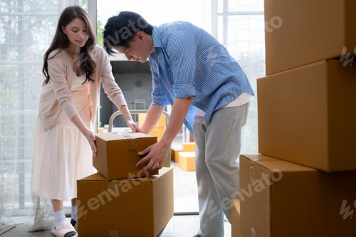 Preview: Young asian couple moving in new house. Asian man and woman holding boxes.