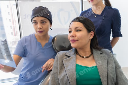 Preview: Young female dentist checking x-ray of a patient.