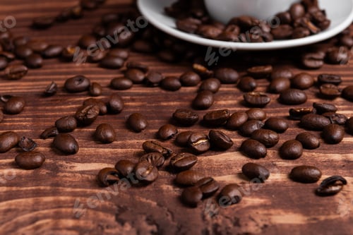 Preview: Roasted coffee beans on a wooden surface close to a coffee cup.