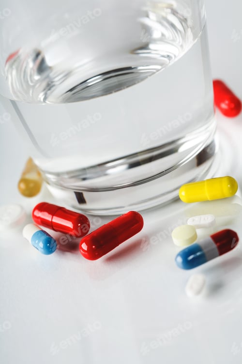 Preview: Medicine pills and capsules with glass of water