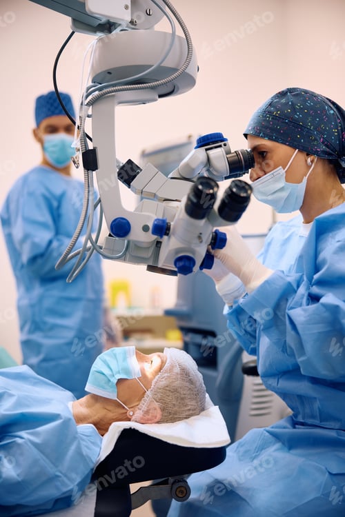 Preview: Medical expert using microscope while performing eye surgery at ophthalmology clinic.