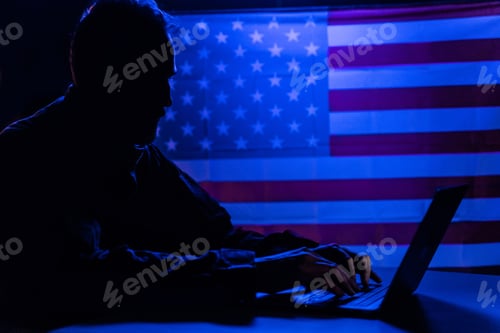 Preview: Hacker with laptop and USA flag in background. Cyber attack concept