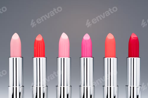 Preview: Close-up view of collection of fashionable glossy lipsticks in row isolated on grey