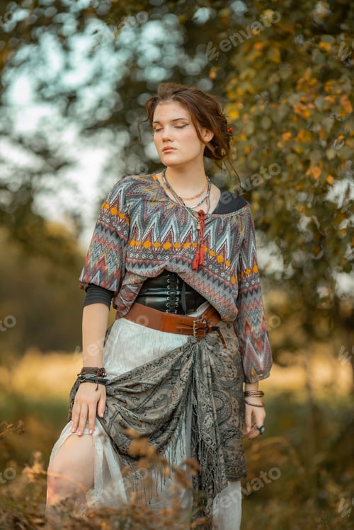 Preview: Young woman in boho style clothes posing in autumn forest