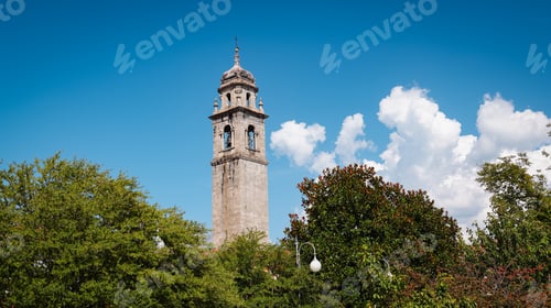 Preview: Historic clock tower surrounded by lush greenery in Verbania Italy on a sunny day