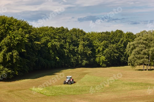 Preview: Tractor mowing grass. Meadow sorrounded by forest. Agriculture industry