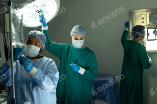 Preview: Two diverse female surgical techs adjusting light and iv bag in operating theatre during operation
