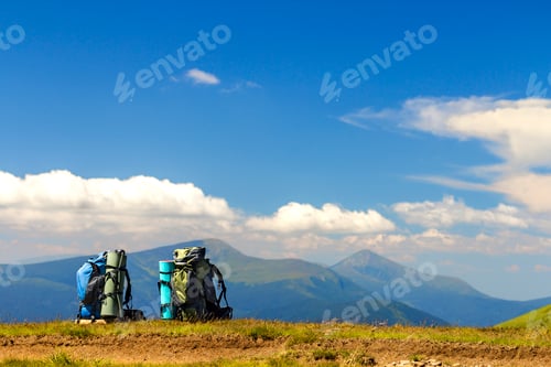 Preview: Two hikers backpacks on a grass with mountain peaks in view. Carpathian mountains, Ukraine