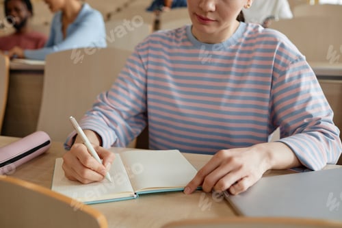 Preview: Schoolgirl making notes in notebook at lecture