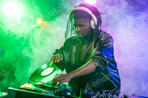 Preview: professional african american DJ in headphones with sound mixer in nightclub