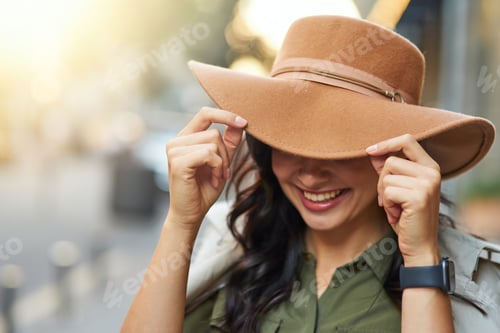 Preview: Portrait of a young playful caucasian woman adjusting hat and smiling while walking on warm autumn