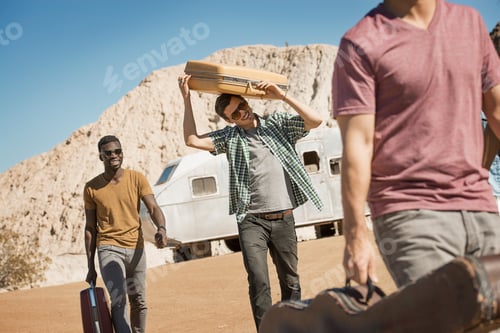 Preview: A group of people walking in a line in open desert country, carrying their cases, on a road trip.