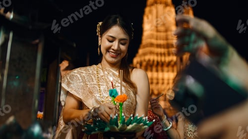 Preview: Thai woman celebrating loi krathong festival, holding a krathong at wat arun, bangkok
