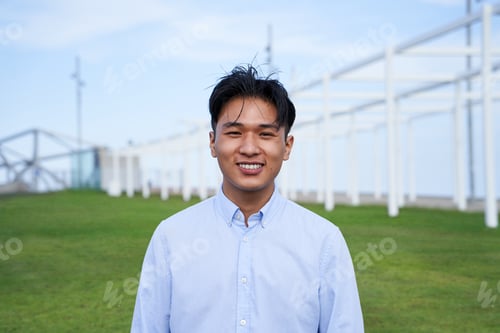 Preview: Looking at the camera portrait of an Asian guy Smiling young standing outdoors