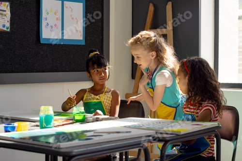 Vista previa: In school, three young girls are focusing on painting in art class