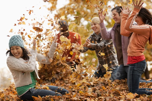 Preview: A group of men and women throwing fallen autumn leaves in the air