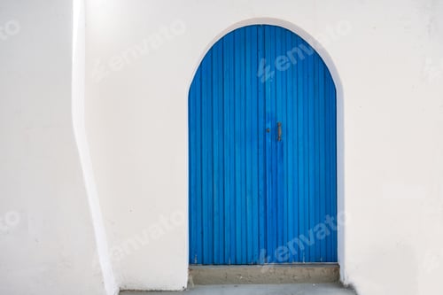 Preview: Blue wooden door on white house wall background front view. Greek island traditional architecture.
