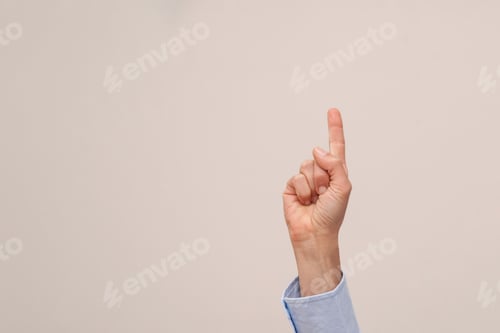 Preview: close up of hand pointing index finger upwards on beige background with copy space