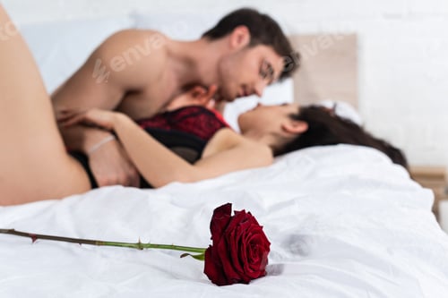 Preview: Selective focus of red rose near passionate couple hugging on bed