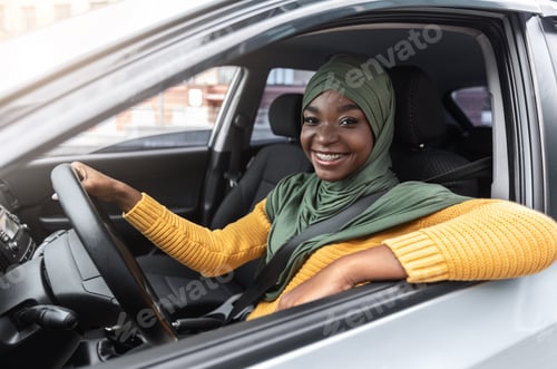 Preview: Joyful Black Muslim Lady Sitting In Car, Enjoying Driving Her New Auto
