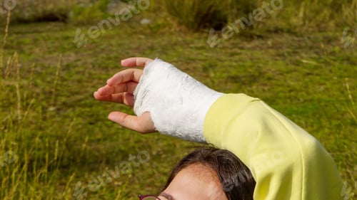 Preview: Woman's arm encasted in plaster against a field